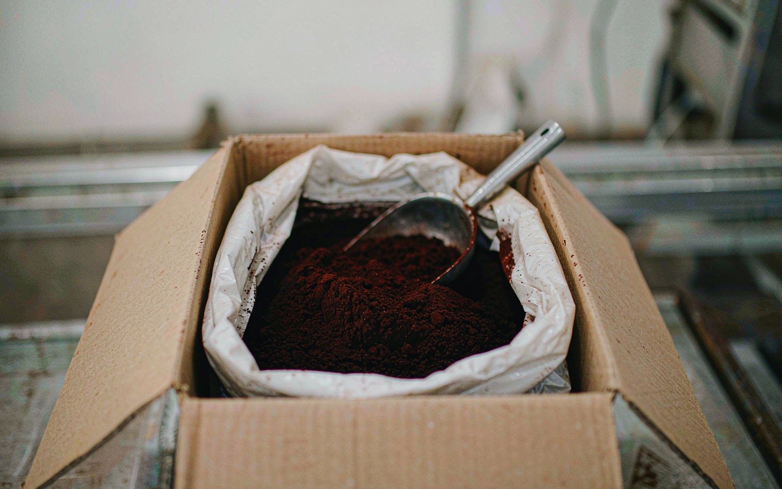 An open food grade carton of dark reddish brown annatto extract powder with the white inner bag folded open