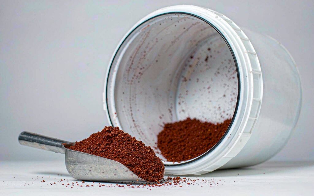 Rhodiola rosea extract powder being scooped out of a 25 kg fibre drum that has been laid on its side in the packing area